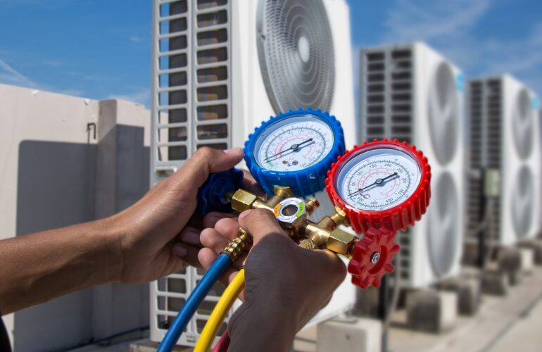 HVAC-installateur controleert met een manometerset de airco-units op een dak