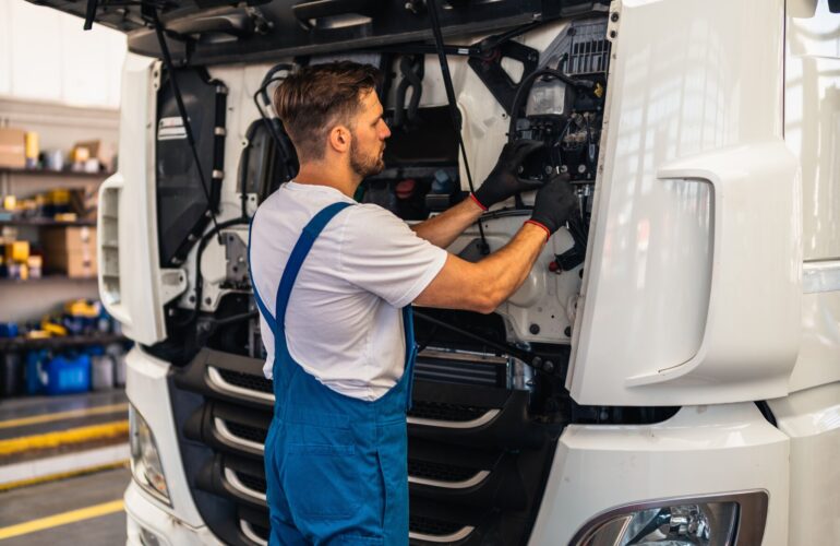 Vrachtwagenchauffeur CE aan de open cabine van een witte vrachtwagen